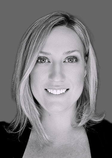 Black and white portrait of a woman with shoulder-length blonde hair, smiling at the camera.